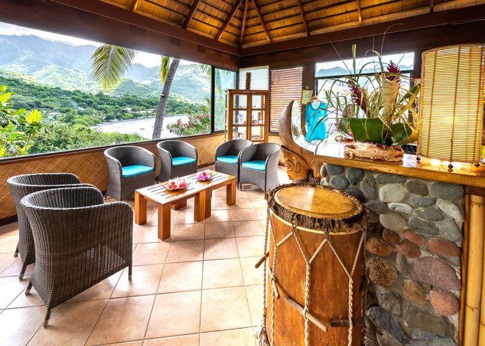 Vue sur la baie de Taiohae depuis la réception, bar en pierre et fauteuils - Hôtel Le Nuku Hiva by Pearl Resorts 3***