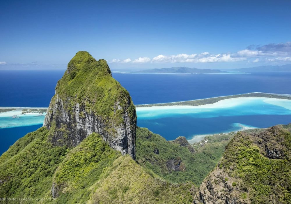 vue aérienne depuis un hélicoptère, du mont Otemanu à Bora Bora à première plan. Lagon turquoise et océan au second plan et îles de Raiatea et Taha'a en arrière plan