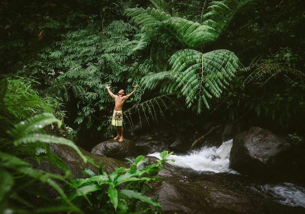 Polynésien dans la forêt de Tahiti devant une cascade
